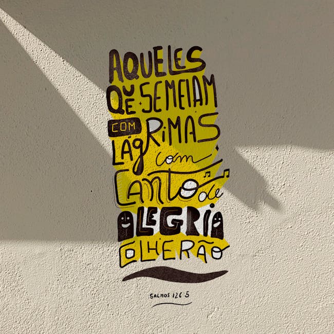 A Portuguese mural featuring inspirational hand-lettering with strong sunlight creating shadow patterns.
